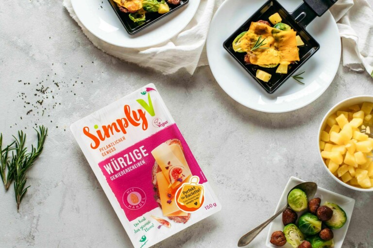 Simply V Genießerscheiben Würzig Verpackung neben Raclette-Pfännchen